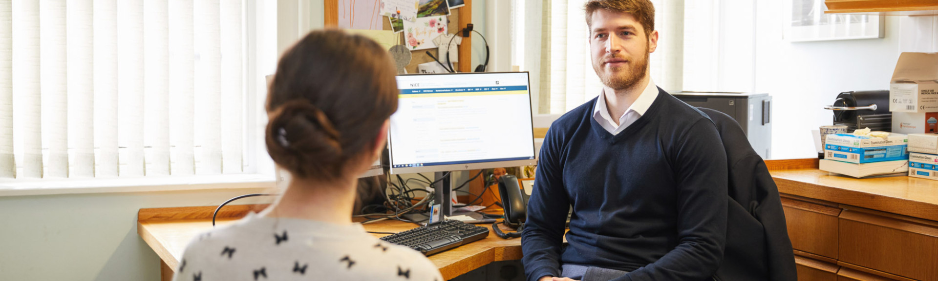 A photo showing a pharmacist speaking to a patient