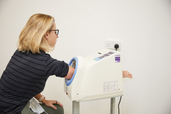 A patient showing a patient using the blood pressure machine in the reception area