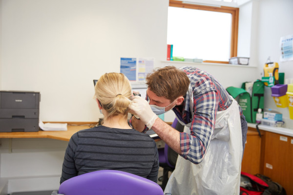 A photo showing a patient having their ears checked