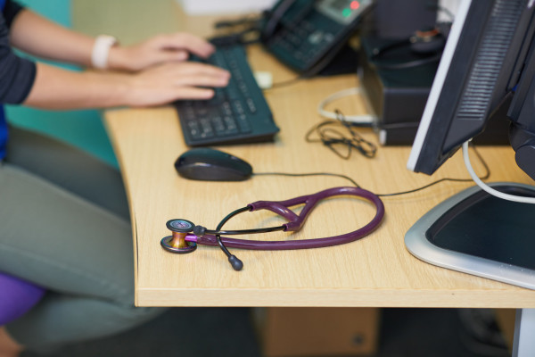 A photo showing a work desk with a computer and stethoscope